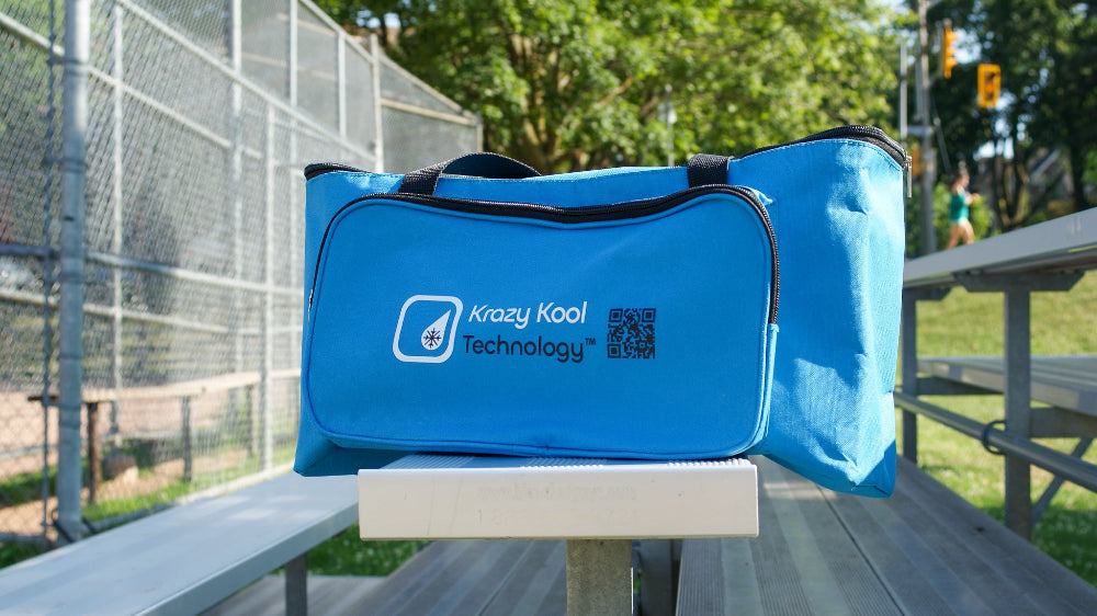 Blue thermal duffel bag with Krazy Kool Technology logo on a baseball metal bench outdoors in ball park stands.