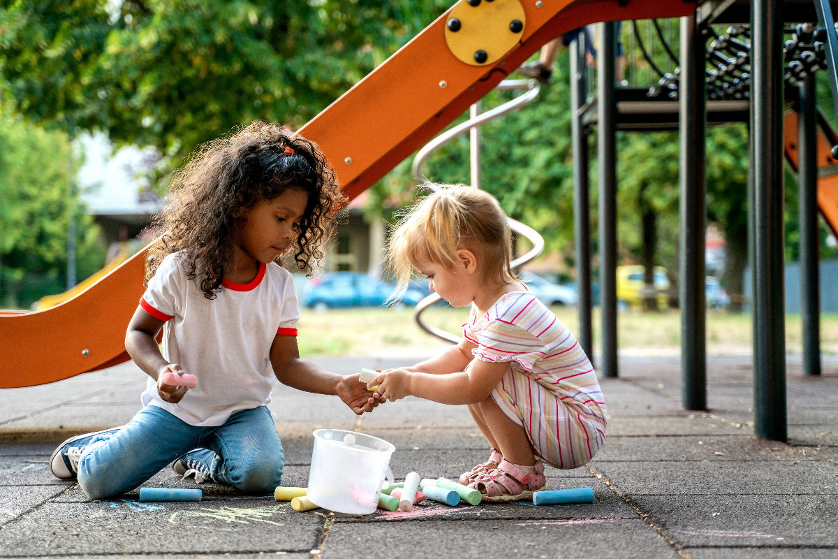 Two children playing with chalk on a playground