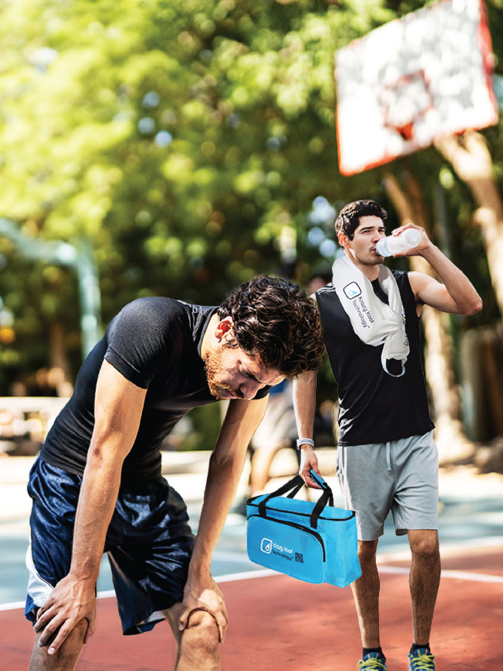 Male friends casually play pick up basketball on outdoor court with one man exhausted and overheating while the other player is happily drinking water and wearing the Krazy Kool Technology cold therapy System on his body and carrying the Thermal Storage Bag in his hand.