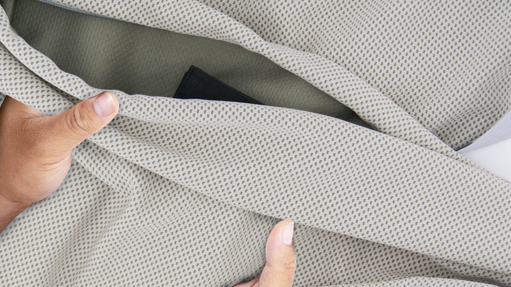 Close-up of Hyper-Evaporative Shell with zipper and black loop fasteners, showing hands feeling the breathable and light fabric, highlighting its breathable, cooling material for cold therapy and recovery.