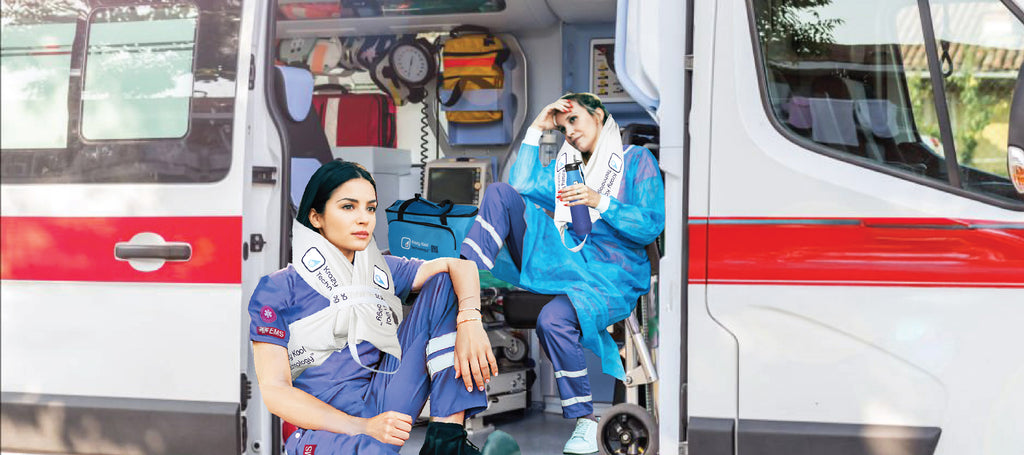 Two female paramedics on the job sitting in the white emergency vehicle after being on-call wearing the Krazy Kool Technology cold therapy systems to help cool them down after a long day.