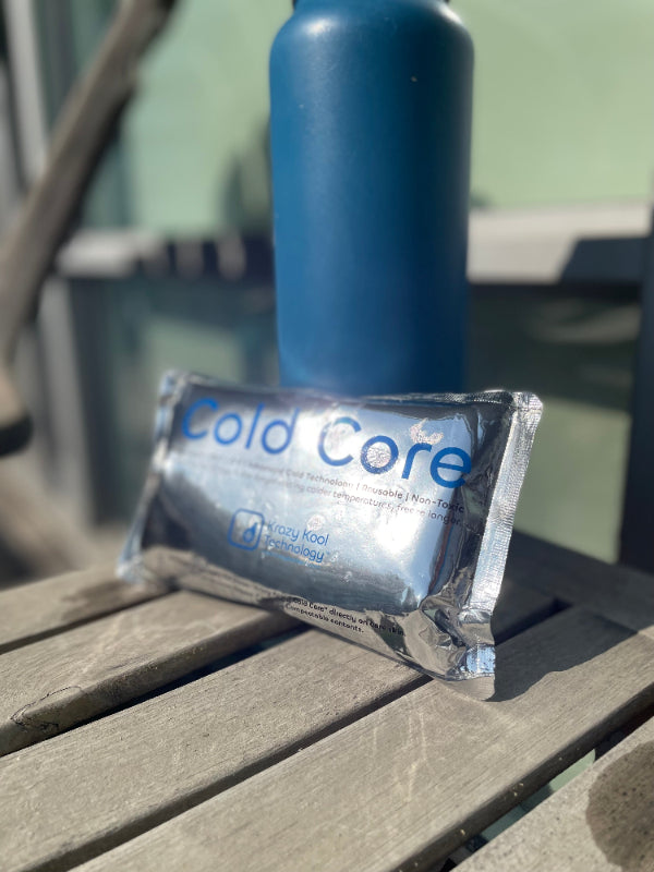 Cold Core product on an outdoor wooden table surface with a blue bottle in the background.