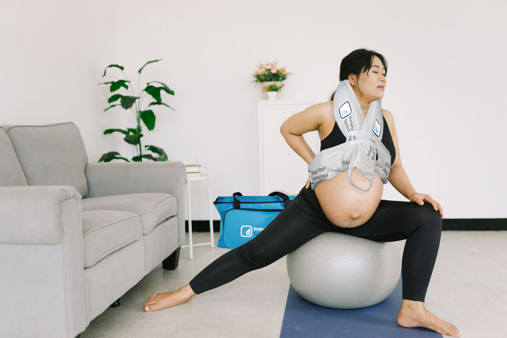 Pregnant woman using a birthing ball with a Krazy Kool Tech cooling System support device in a home setting.